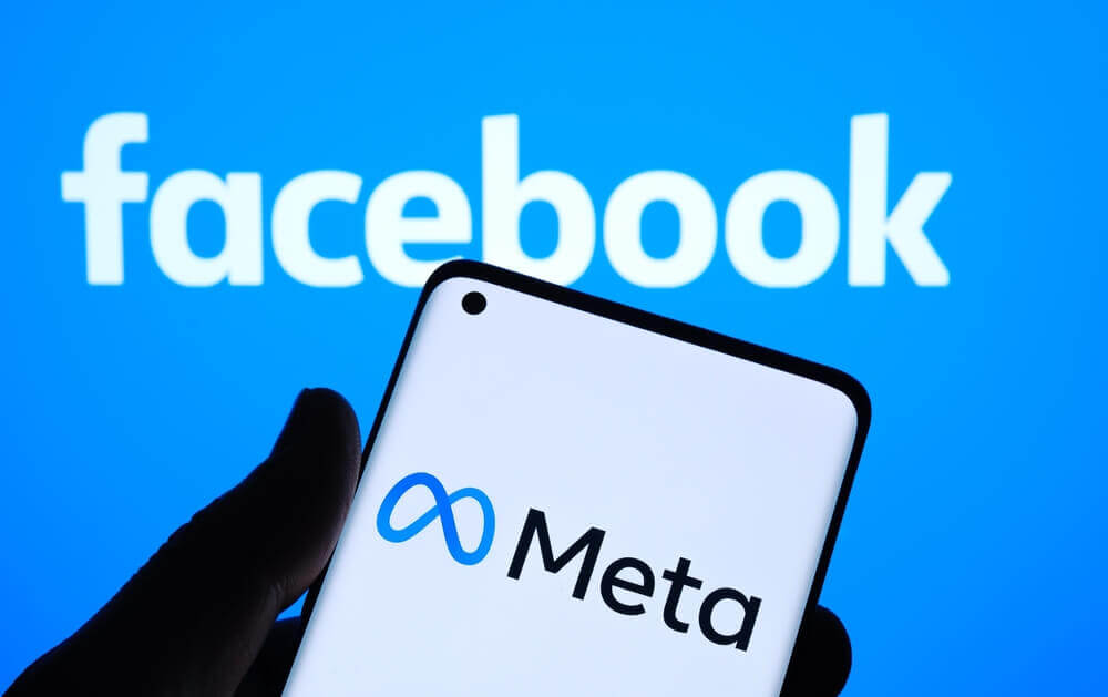 logo meta su smartphone e dietro logo facebook per causa meta facebook