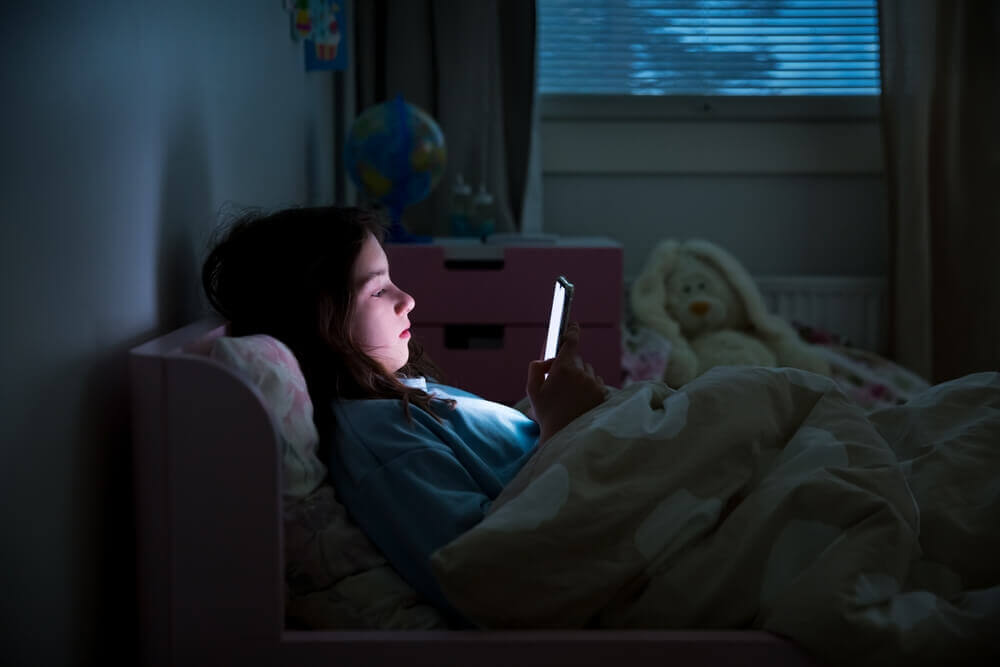 bambina usa smartphone a letto parental control