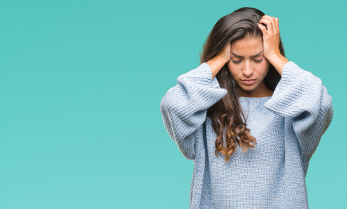 ragazza con capelli lunghi stressata su sfondo celeste