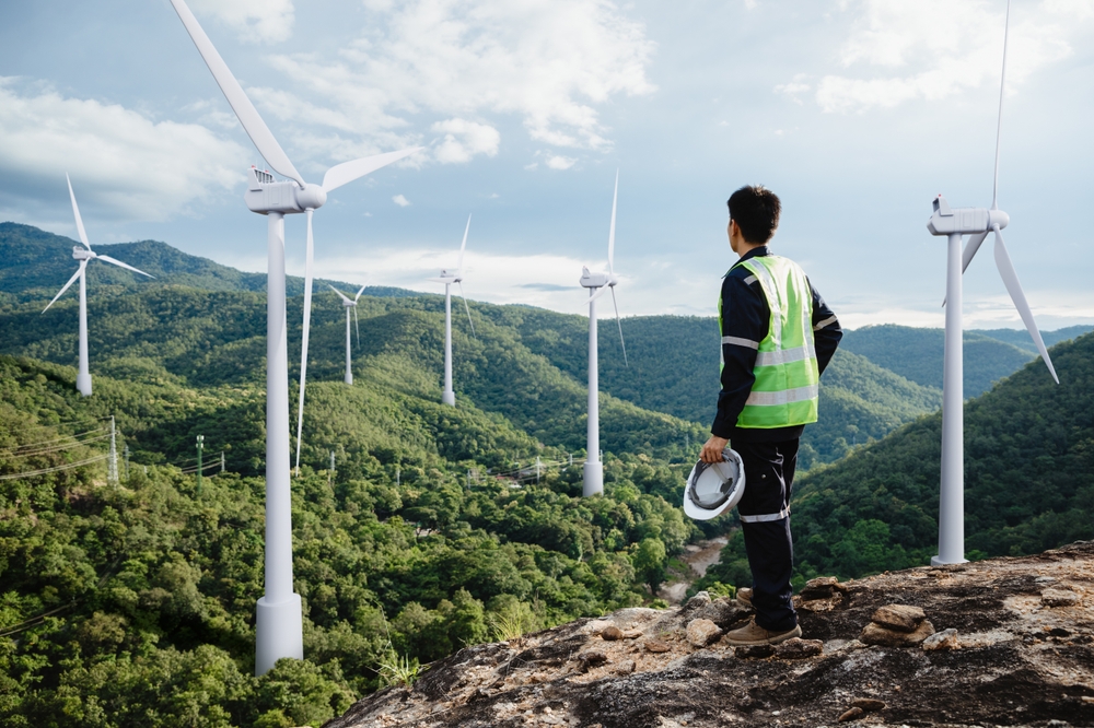 Green economy ingegnere con pale eoliche su paesaggio verde di colline e montagne