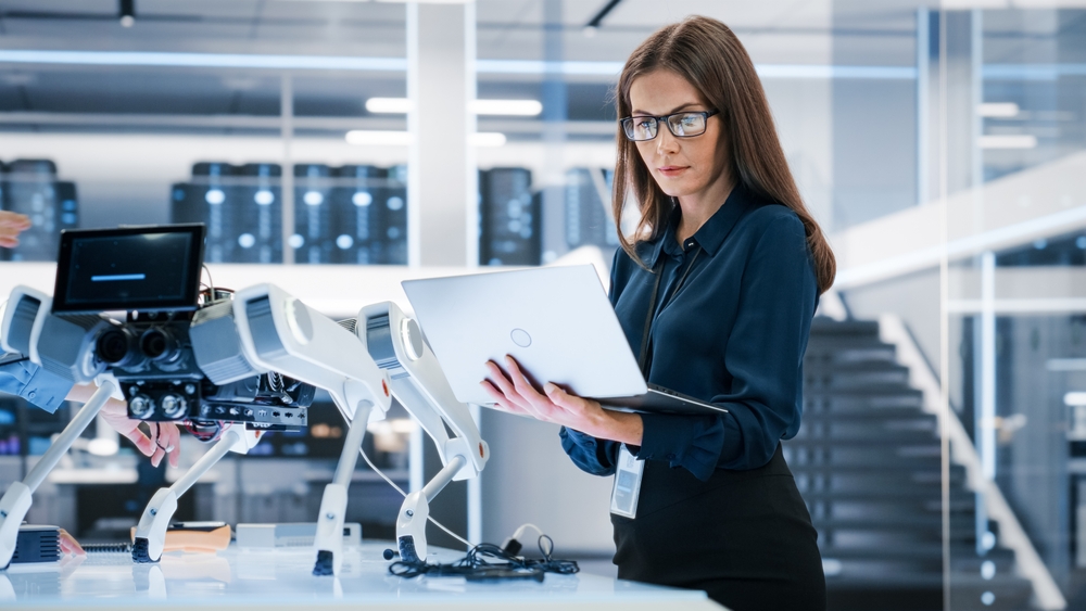 ingegnere informatico con camicia blu e occhiali da vista neri regge pc portatile