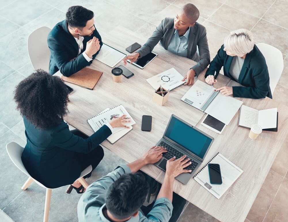 meeting composto da cinque persone su tavolo chiaro di legno