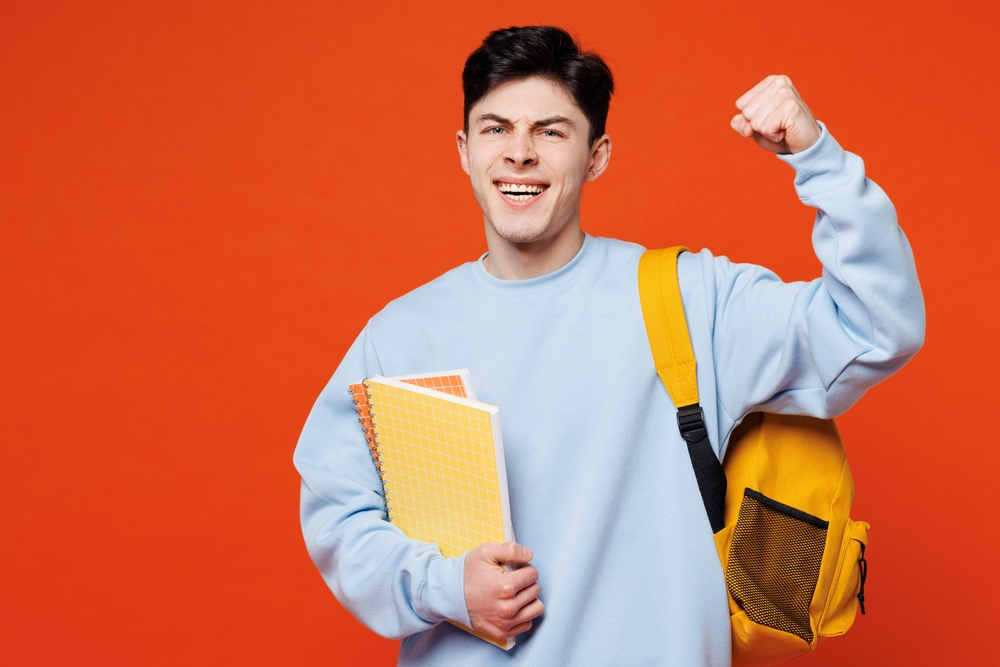 studente con libri di testo sottobraccio e zaino in spalla su sfondo arancione