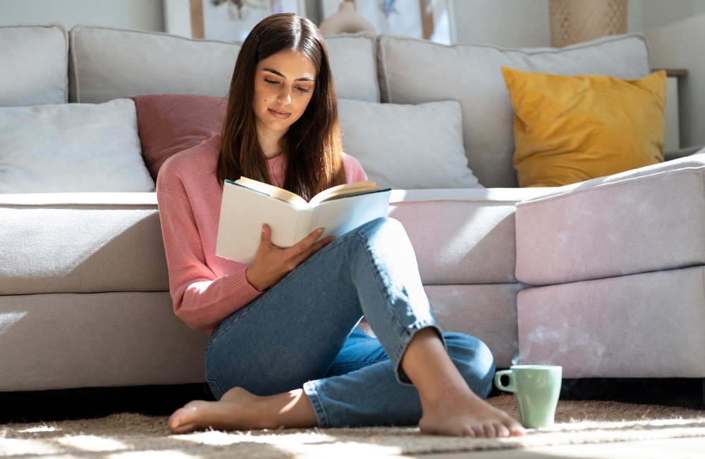 ragazza seduta a terra studia con i libri in mano