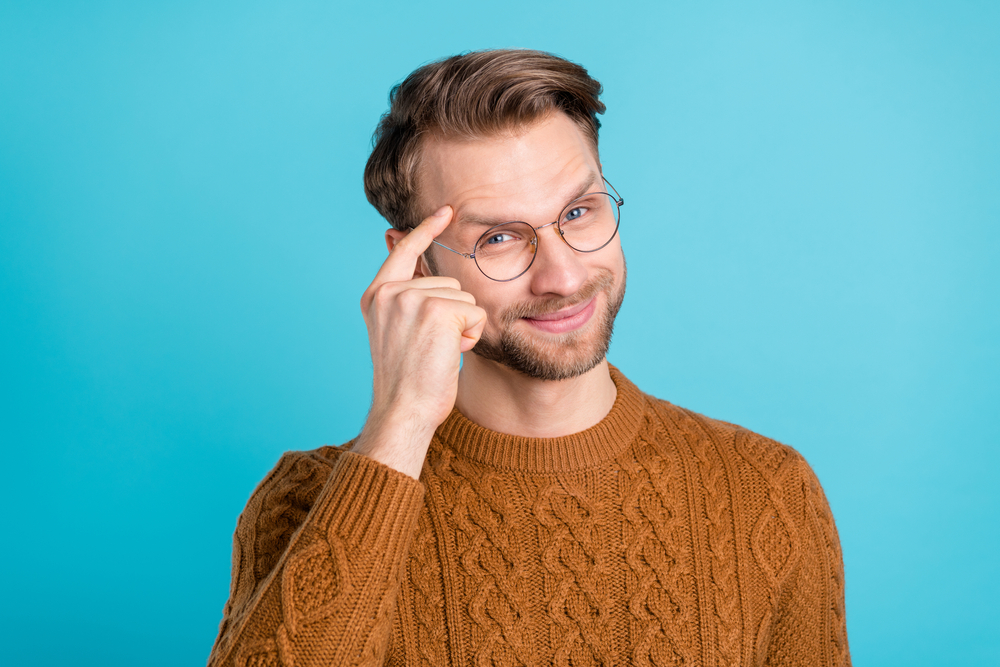 ragazzo con occhiali con maglione beige su sfondo celeste