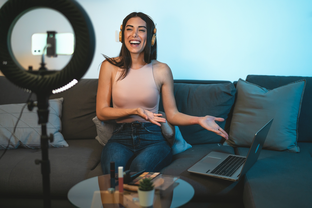 influencer sul divano con pc cuffie orecchio e ring light