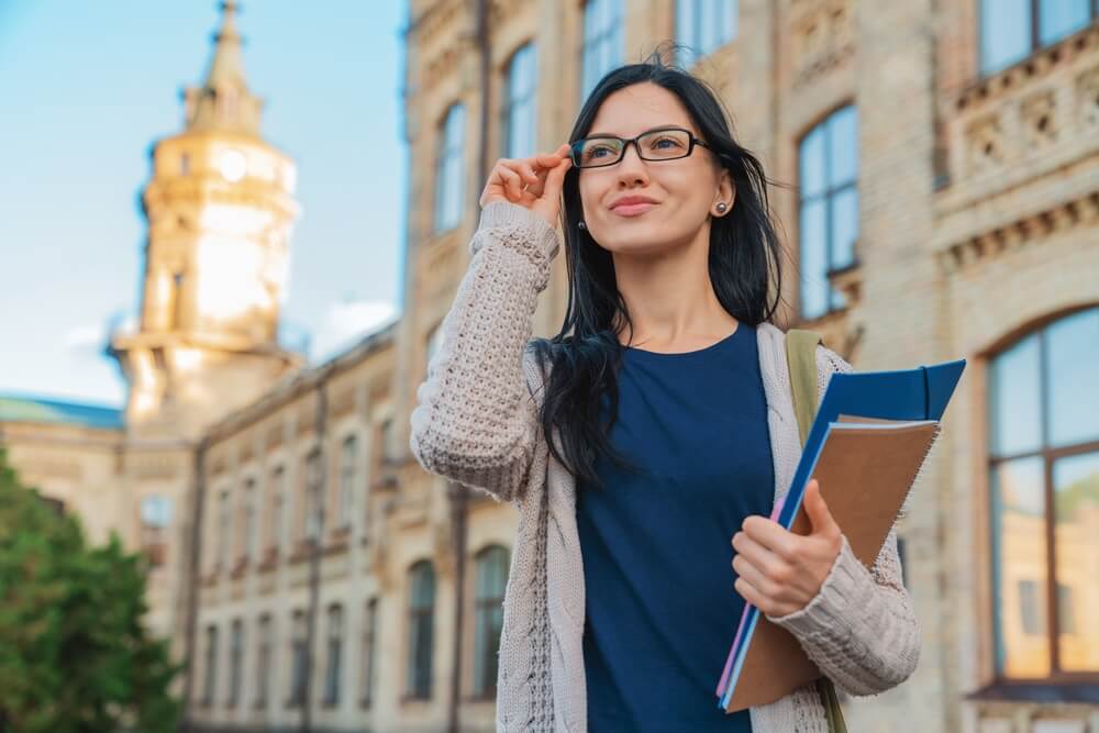 studentessa con capelli neri libro in mano e occhiali da vista