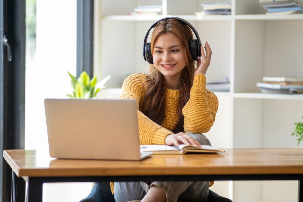 studentessa fa lezione online con cuffia alle orecchie e pc sulla scrivania