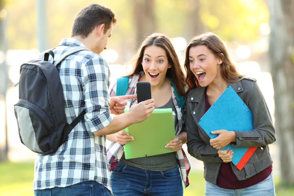 studenti universitari che guardano lo smartphone con stupore