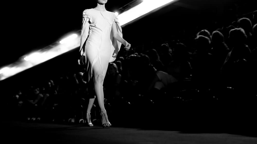 foto in bianco e nero di modella in passerella con abito bianco