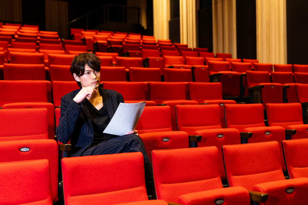 critico arte sulle poltrone rosse di un teatro