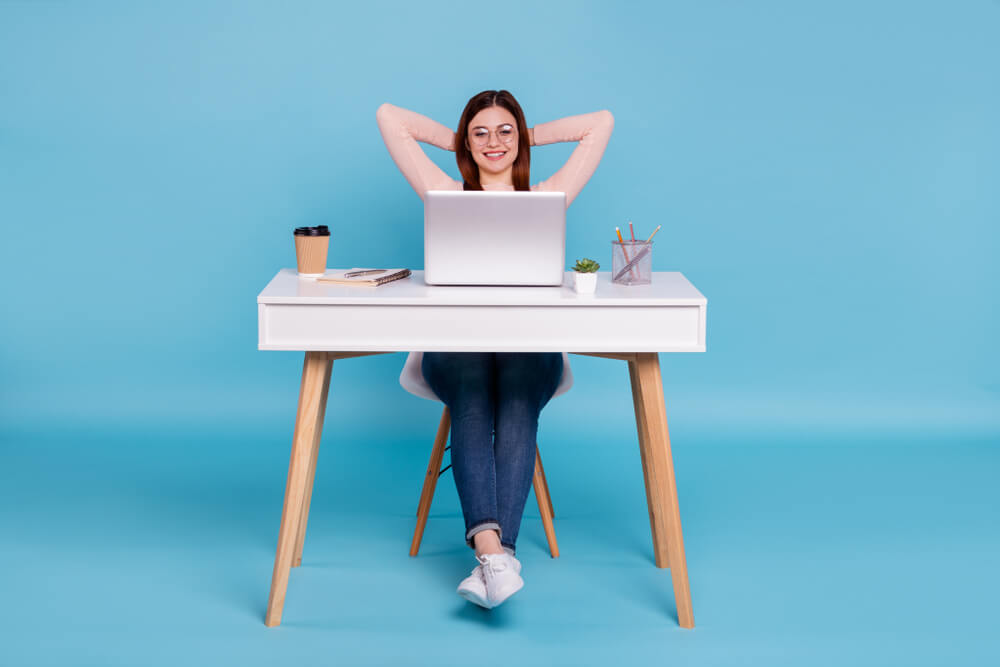 ragazza felice alla scrivania davanti al pc su sfondo celeste