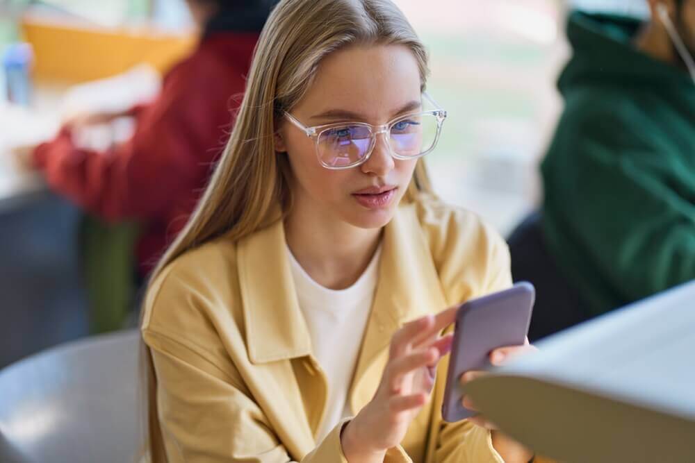 adolescente usa smartphone in classe, il ministro valditara ha vietato l'uso degli smartphone alle superiori dal prossimo settembre