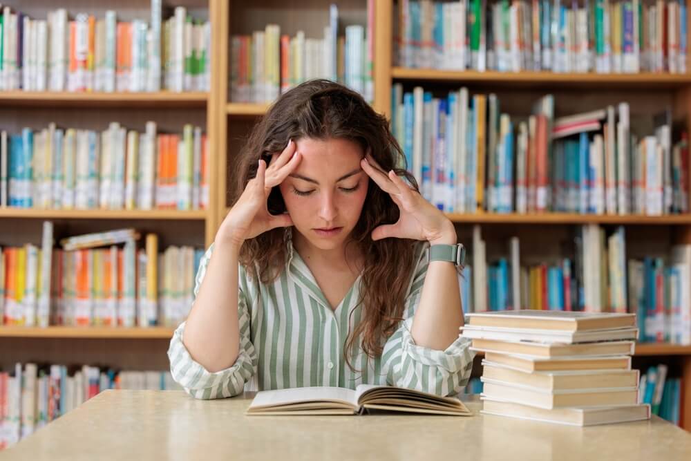 studentessa con la testa tra le mani si concentra sui libri
