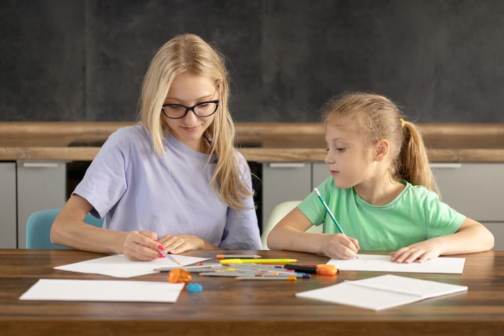 pedagoga con bambina alla scrivania di scuola