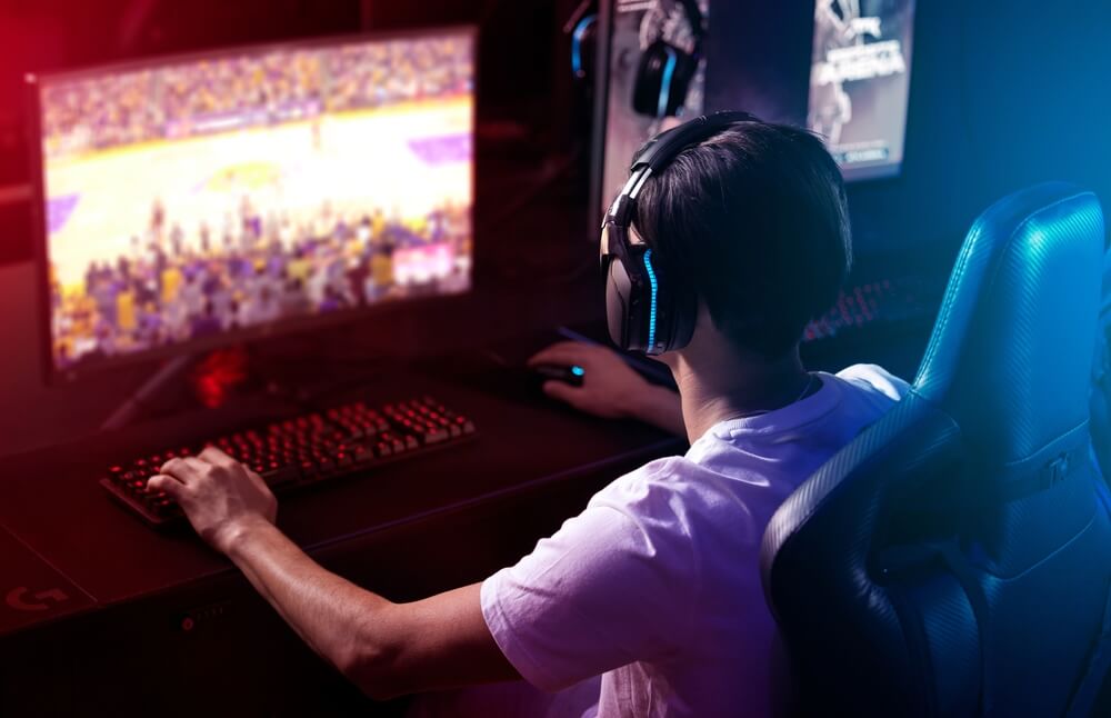 gamer al pc, di spalle, con cuffie alle orecchie
