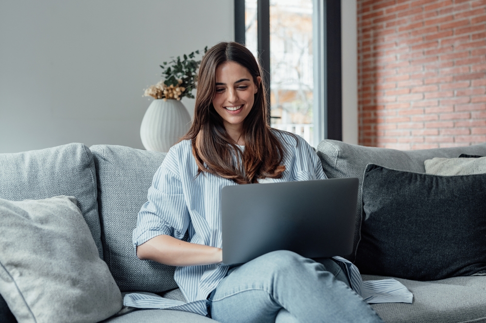 ragazza sorridente al pc su un divano bianco