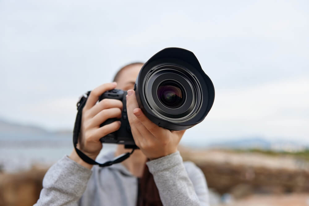 Giovane fotografa regge macchina fotografica in un giorno nuvoloso