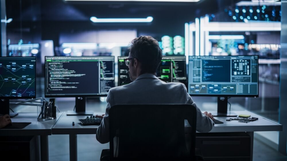 Vista posteriore di un giovane ingegnere che lavora su computer in un ambiente di ufficio tecnologico