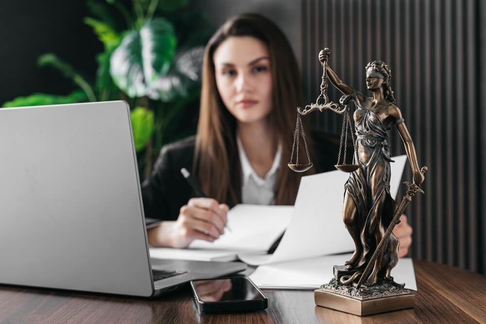 Avvocato donna lavora su un computer portatile con una bilancia della giustizia sul tavolo di un tribunale