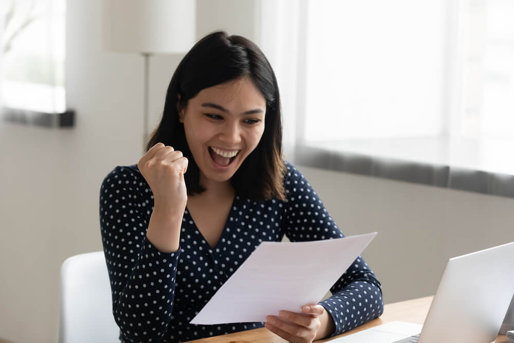 Studentessa legge una lettera con buoni risultati degli esami di prova ed esulta