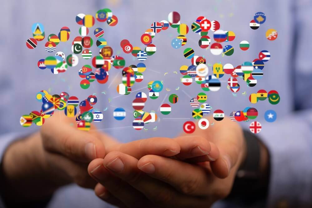 uomo tiene in mano icone delle bandiere di tutto il mondo per rappresentare laurea in comunicazione interculturale