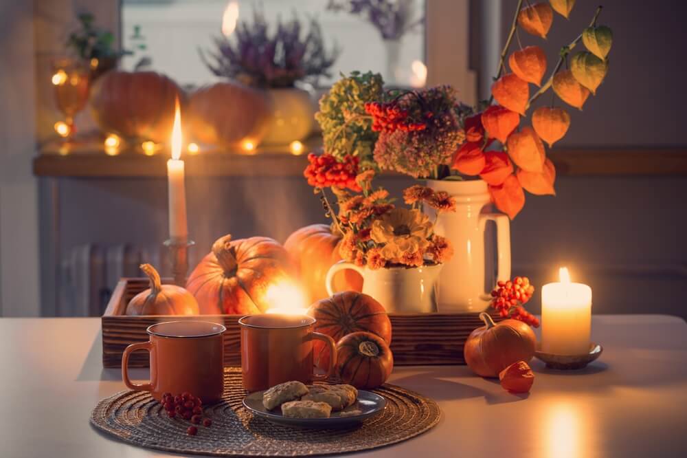 Two,Orange,Cups,Of,Tea,And,Autumn,Decor,With,Pumpkins, Decorazioni di Halloween si una tavola: zucche, fiori e candele