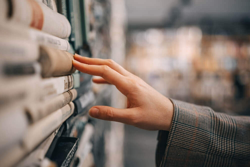 mano sceglie tra libri su scaffale per rappresentare articolo che parla degli sbocchi lavorativi più interessanti con laurea in artistico audiovisivo e spettacolo