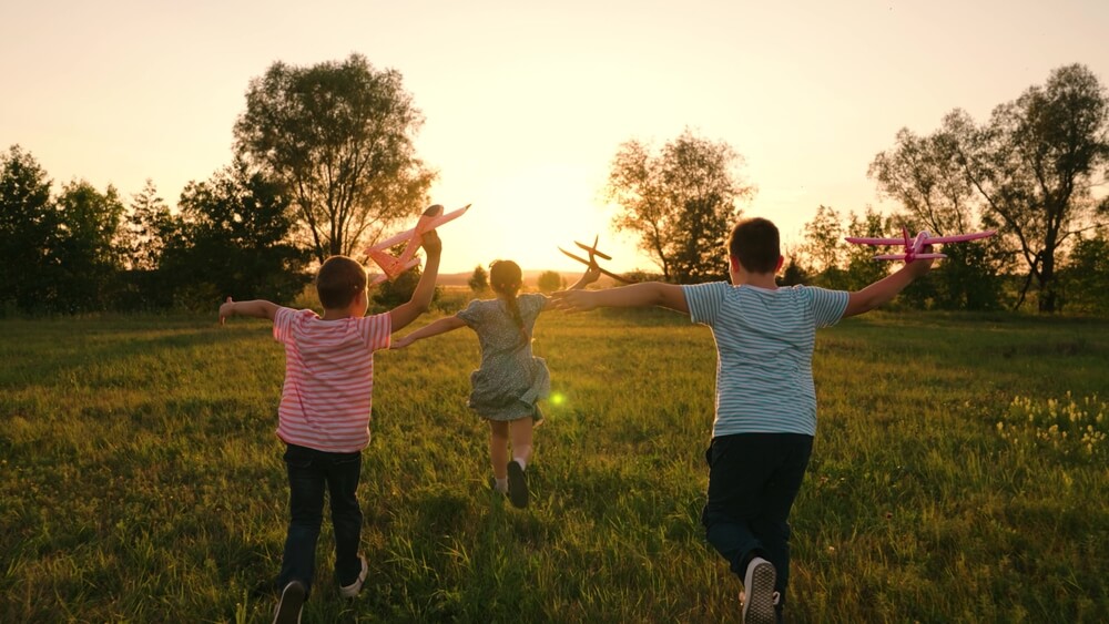 Bambini corrono su un prato al tramonto
