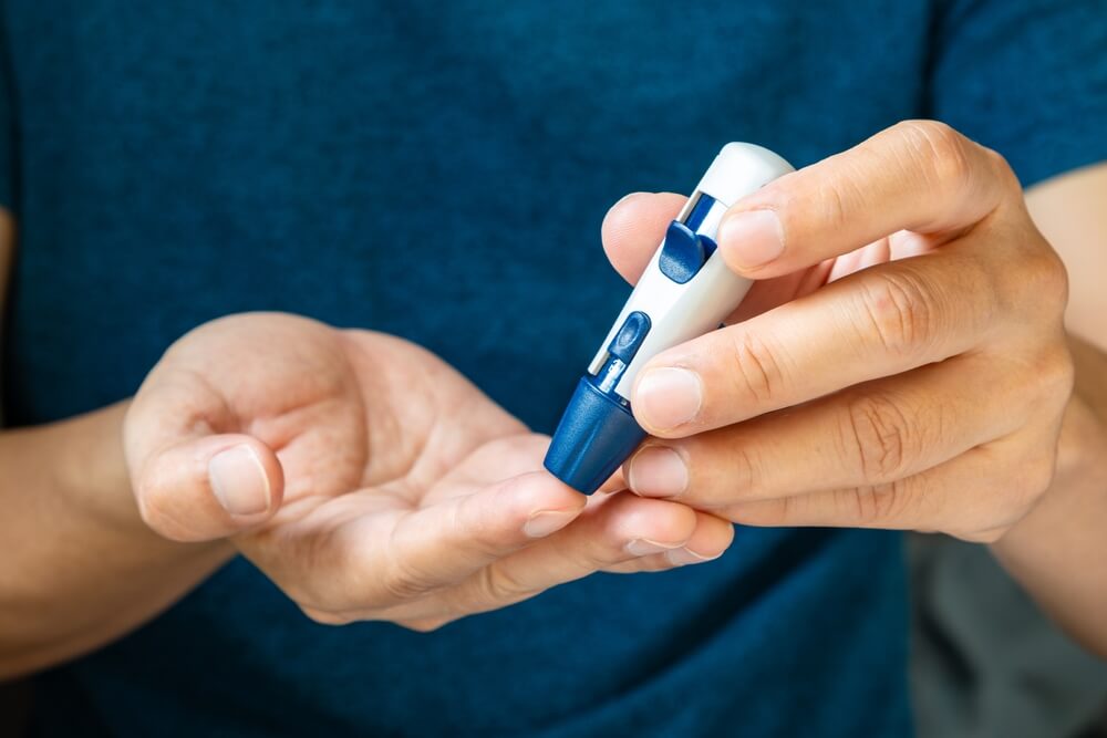 Uomo con diabete, con mani in primo piano, si misura la glicemia