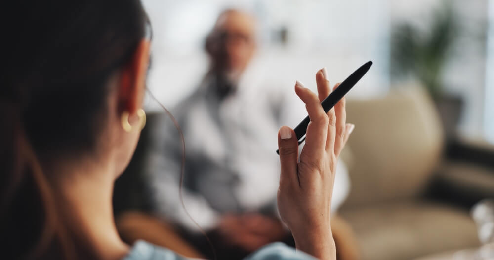 Psicologa inquadrata di spalle, con penna in mano, durante seduta