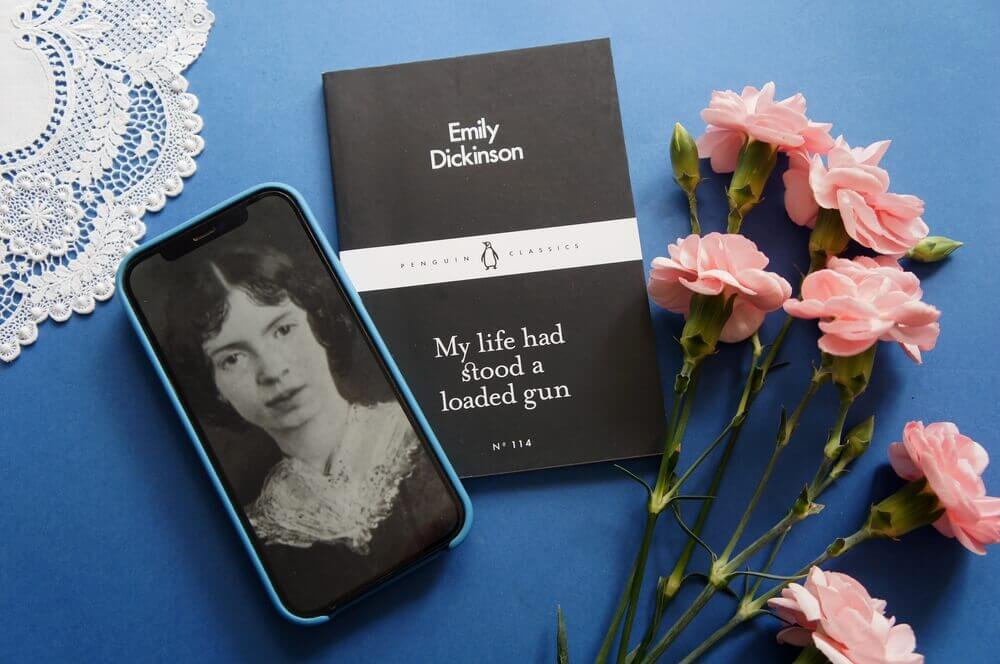 raccolta di poesie e immagine di emily dickinson su un tavolo con fiori rosa