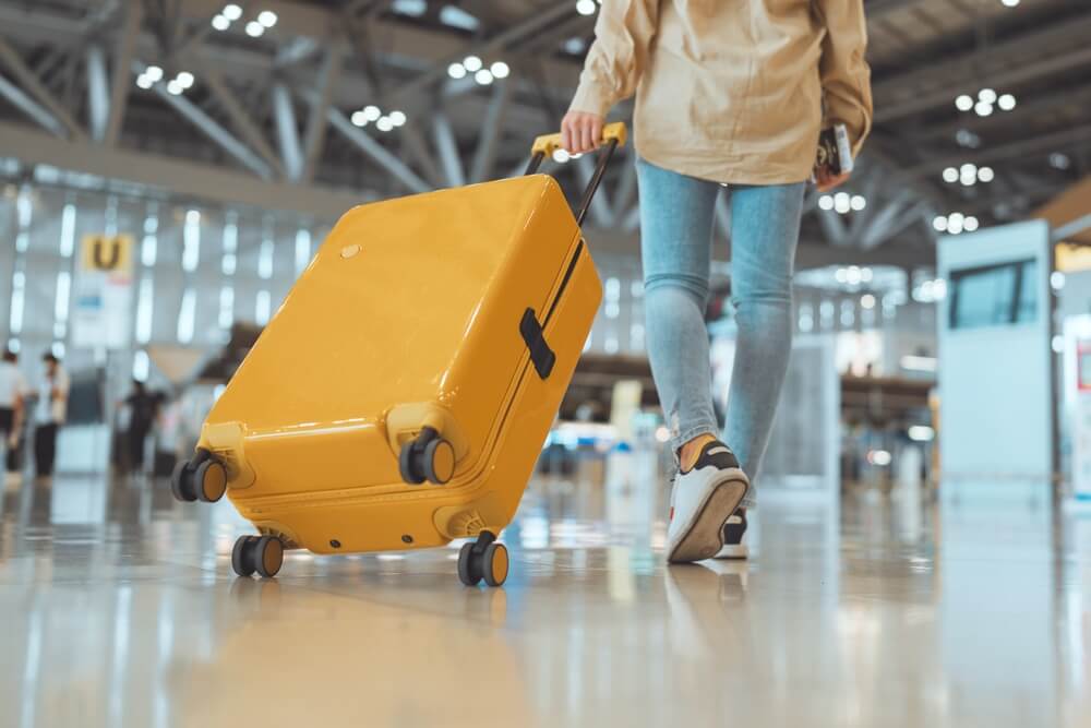Ragazza con trolley giallo in aeroporto