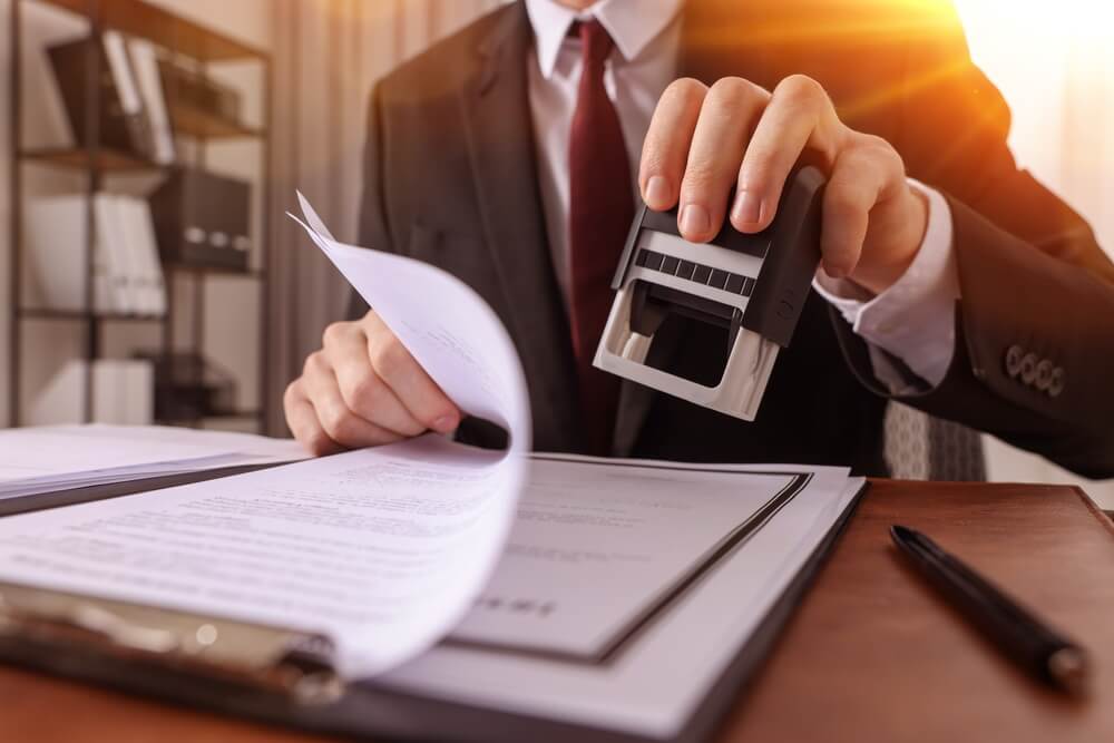 Notary,Stamping,Document,At,Table,In,Office,,Closeup Notaio timbra degli atti sulla scrivania
