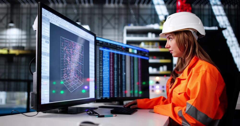 Ingegnere civile donna lavora al pc con indosso una tuta rifrangente e un casco