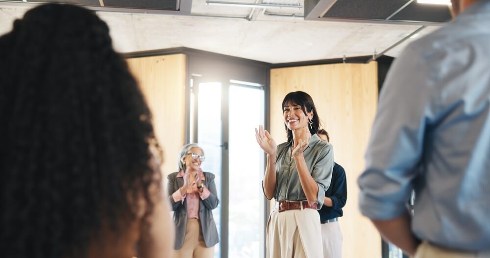 Giovane formatore aziendale applaude con personale in cerchio