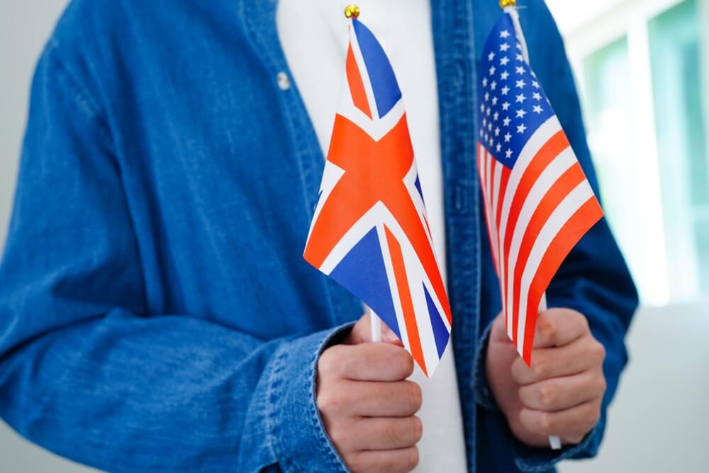 Learn,English,Language,,Asian,Teenage,Student,Hold,Book,With,Flag Studente di lingue regge bandierine Gran Bretagna e Stati Uniti