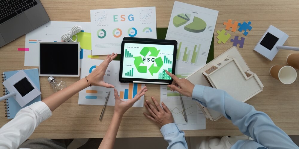 Esg manager in riunione discutono di lavoro davanti a dei grafici sulla scrivania