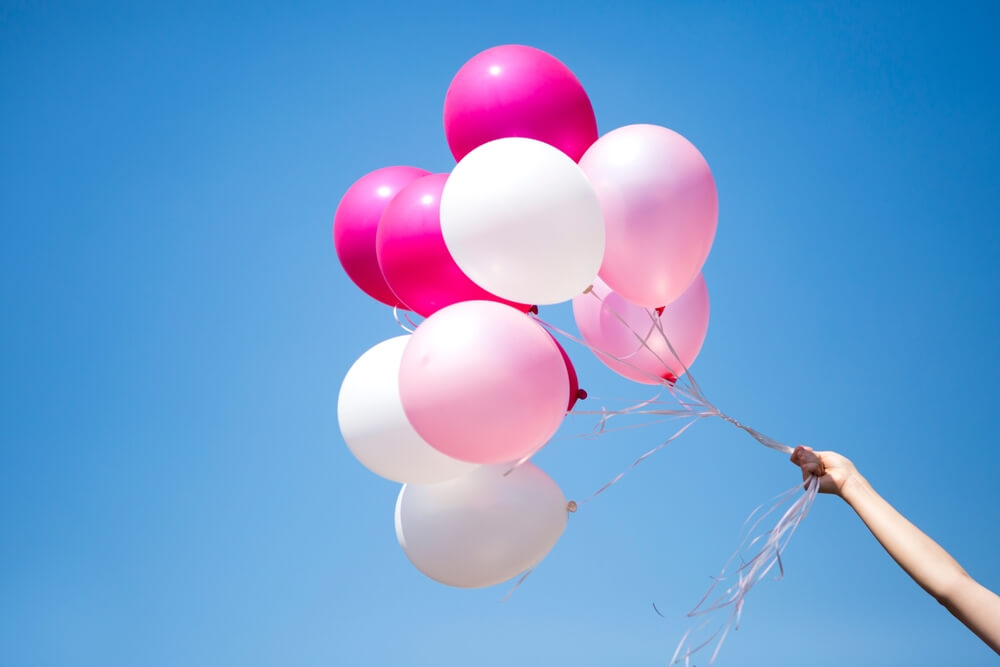 Palloncini rosa e bianchi liberati in cielo da mano femminile