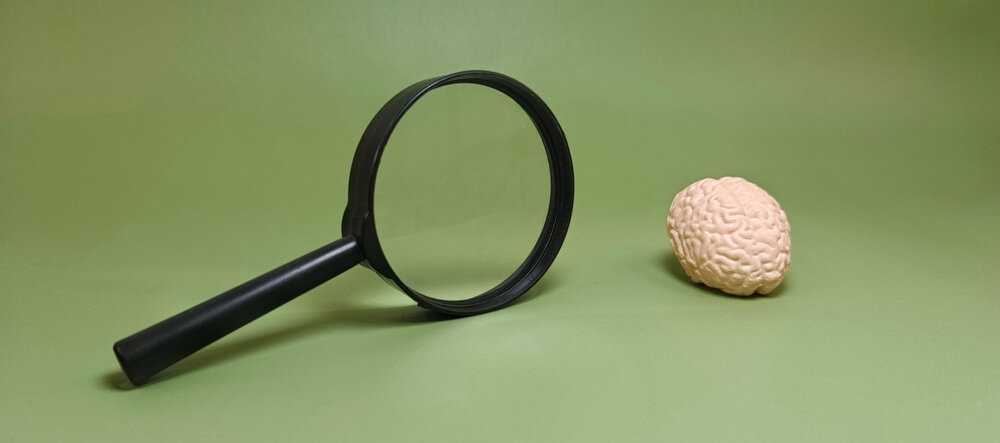 Lente di ingrandimento con cervello su sfondo verde