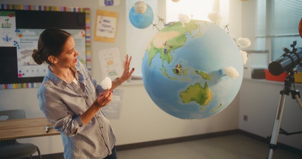 shutterstock_2651896129 insegnante di geografia illustra mappamondo in classe per rappresentare master discipline geografiche a-21