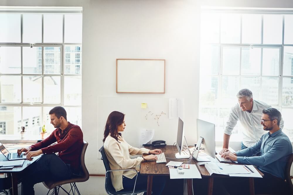 Computer, coworking e uomini d'affari in ufficio con manager per il feedback sul progetto creativo.