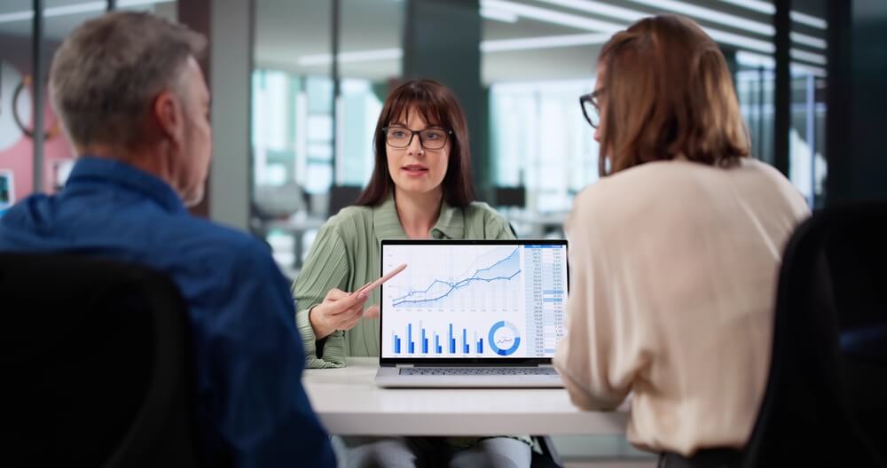 Consulente finanziario illustra grafico ai clienti da laptop