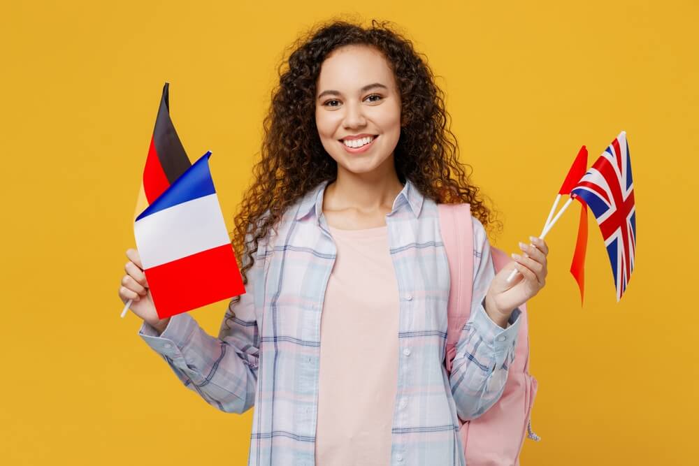 Young,Smiling,Cheerful,Happy,Black,Teen,Girl,Student,She,Wear Ragazza ricci sorride con le bandierine dei Paesi europei per rappresentare il corso di laurea in lingue e letterature europee