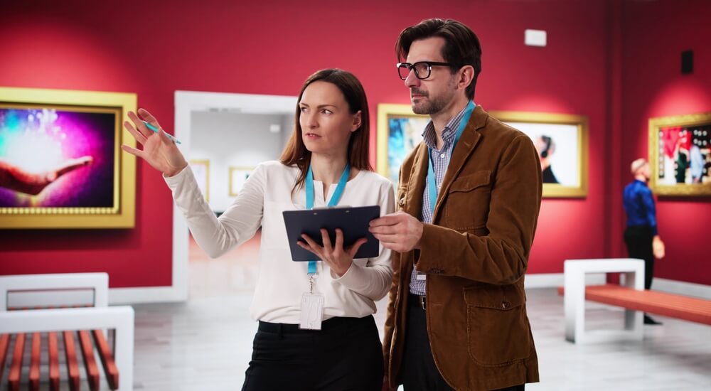 Fine,Art,Gallery,Auction:,Museum,Manager,,Worker,,And,Artist,Talking curatori di mostre danno indicazioni sulla disposizione dei quadri in una galleria dalle pareti rosse