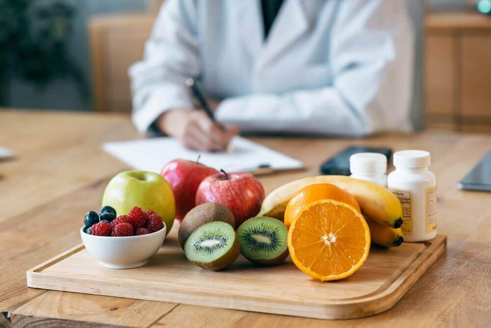 nutrizionista al lavoro con frutta su un tagliere appoggiato sul tavolo per rappresentare laurea magistrale in scienze della nutrizione umana