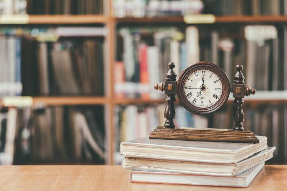 orologio su pila di libri e libreria nello sfondo per rappresentare master insegnare storia e filosofia cdc a-19