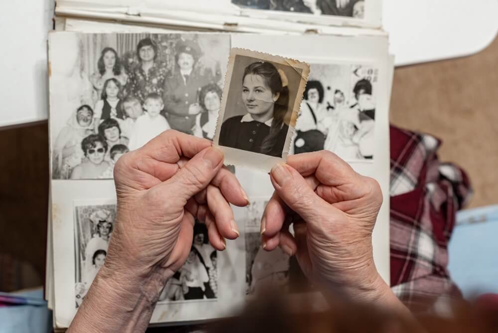 Donna anziana guarda un vecchia album di fotografie in bianco e nero