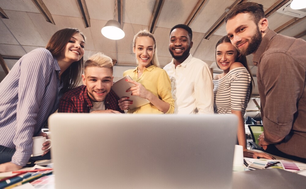 Gruppo di ragazzi a lavoro davanti a un laptop in azienda di comunicazione