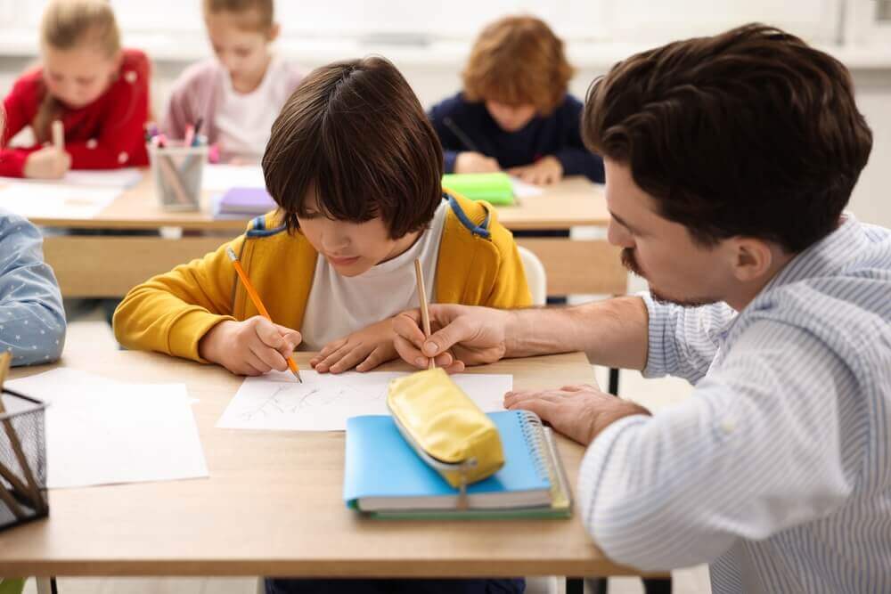 insegnante aiuta alunno per rappresentare master metodologie didattiche bes